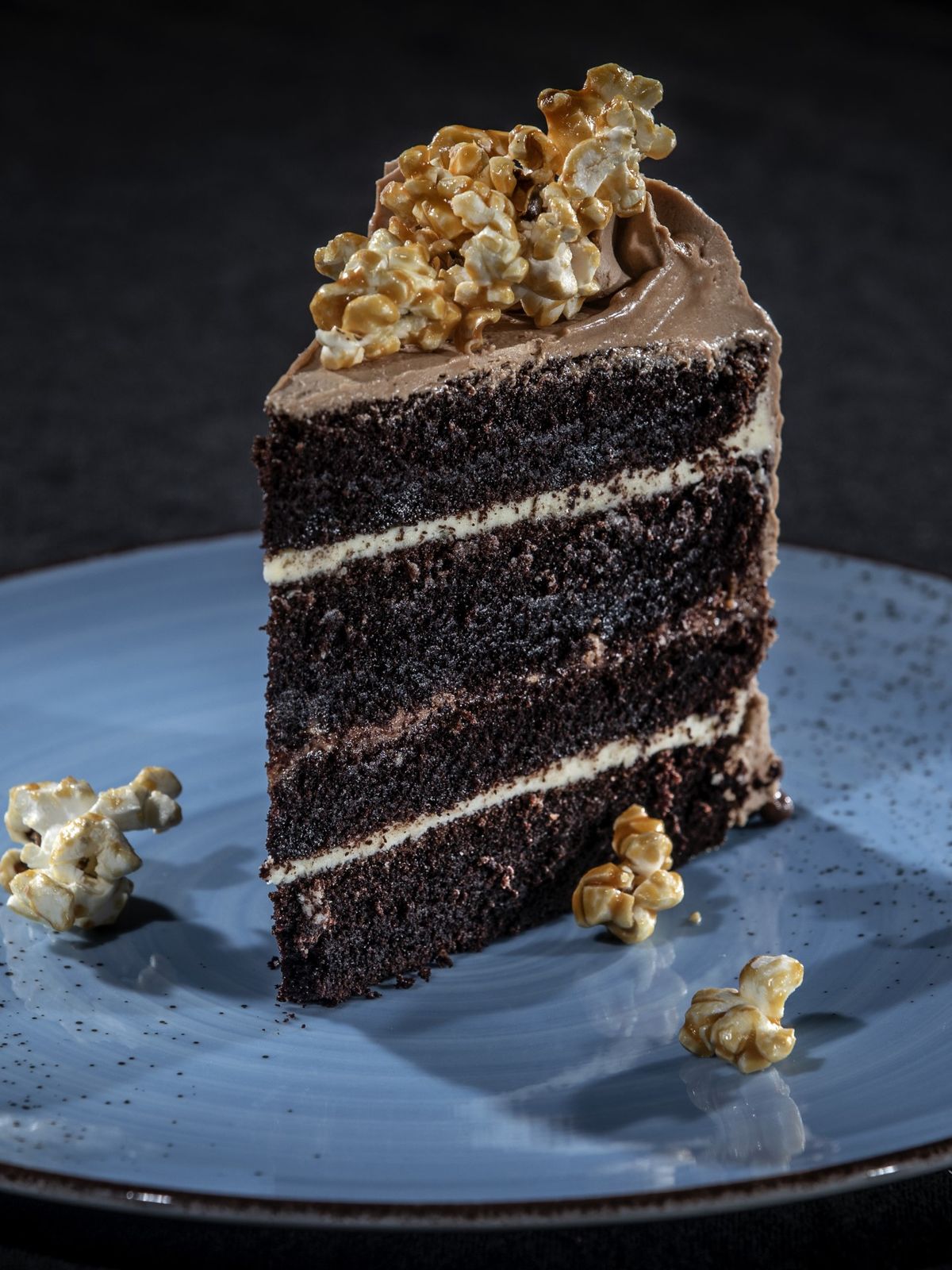 Bit chokladtårta med kolapopcorn på blå tallrik